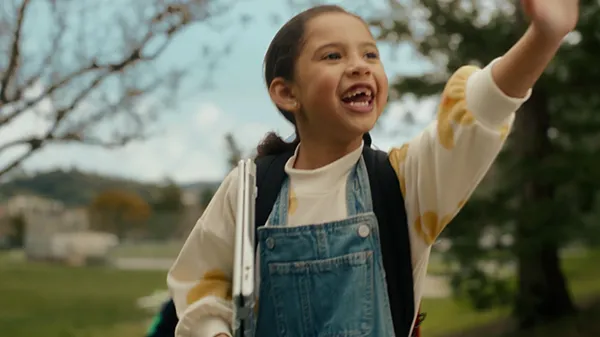 Anna, as an elementary student, laughs as she walks to school with a parent