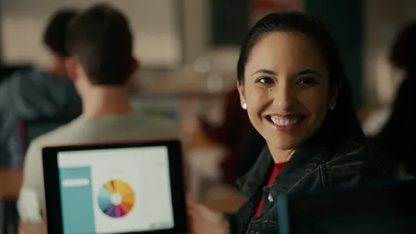 Anna, as a college student, smiling over her shoulder with McGraw Hill's digital program ALEKS visible on her laptop in the background