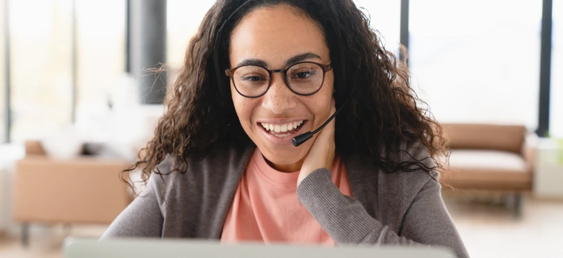 Woman in front of a computer talking with a head set.